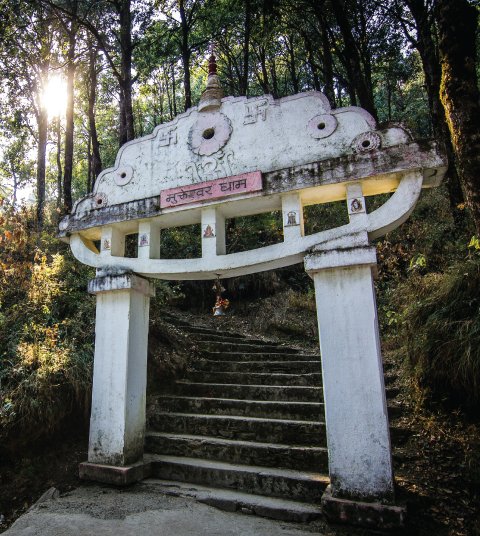 Stone archway entrance to Mukteshwar Dham temple in the forested hills near Ojaswi Resort